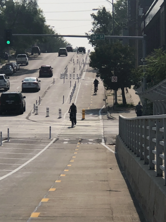 Two people ride the protected bike lane in Omaha which is in a pilot stage along Harney Street between the Midtown neighborhood and downtown.